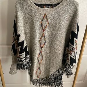 Poncho type sweater with fringe and sleeves